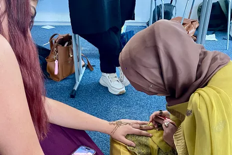 Using henna, a talented student from Pakistan paints all the motifs the heart desires on her guests' skin, from traditional patterns on their palms to characters from the SpongeBob SquarePants series.